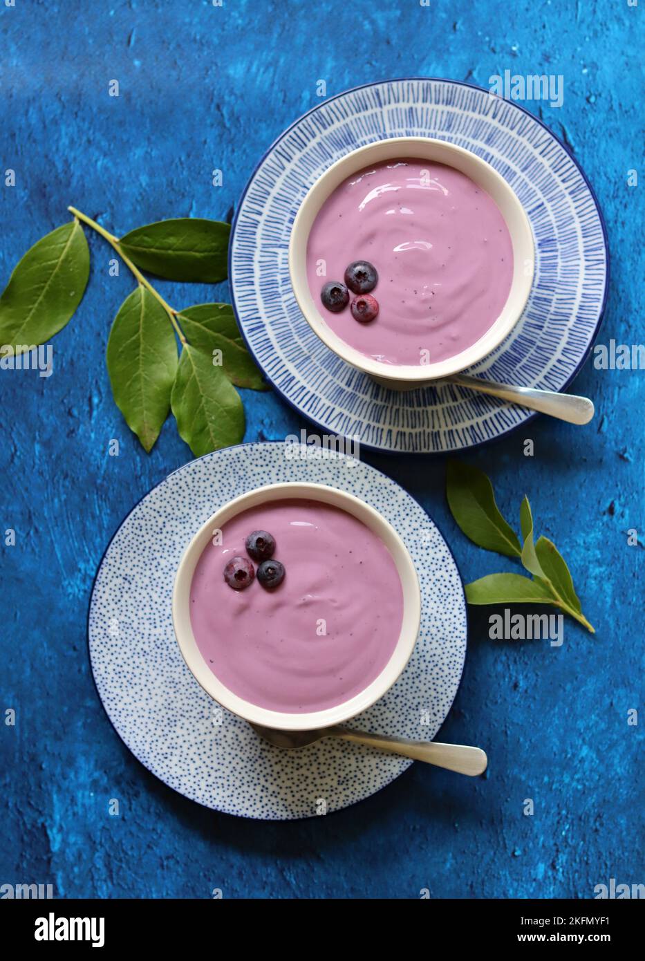 Due ciotole di yogurt al mirtillo su un tavolo. Foto ravvicinata di yogurt naturale con bacche biologiche. Mangiare concetto fresco. Foto Stock