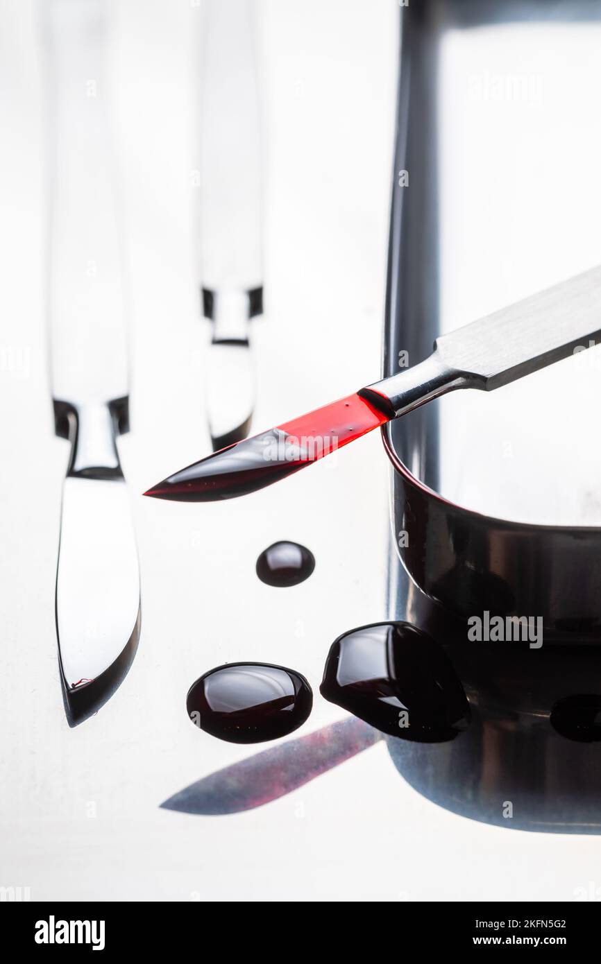 Bisturi chirurgici affilati con sangue su piastra in acciaio inox. Strumenti chirurgici sterili con una piccola quantità di sangue. Foto Stock