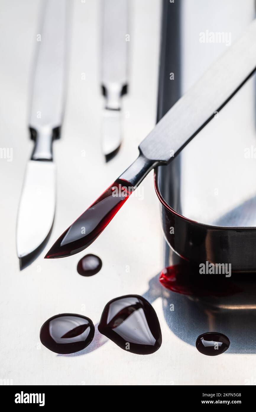 Bisturi in acciaio inox con sangue su piastra in acciaio inox. Strumenti chirurgici sterili con una piccola quantità di sangue. Foto Stock