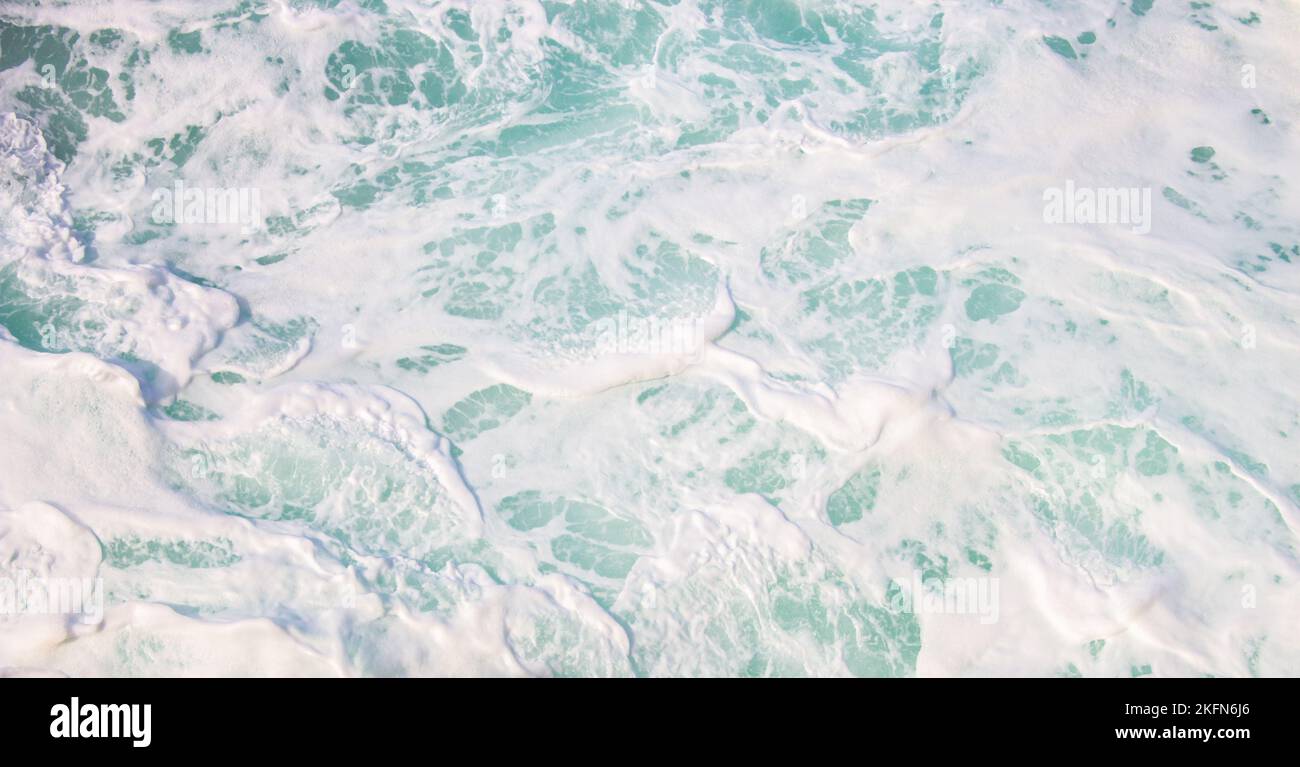 Primo piano in schiuma di mare bianca. Colore acquamarina delle onde con schiuma e bolle. Il potere dell'oceano. Acqua di mare pura in movimento. Spruzzi d'acqua. Foto Stock