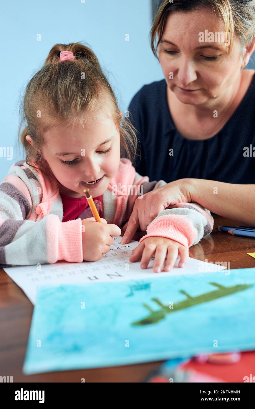 Bambina preschooler imparare a scrivere lettere con l'aiuto di sua madre. Capretto che scrive le lettere, disegni le immagini, fare il roba con la carta, fare un hom Foto Stock
