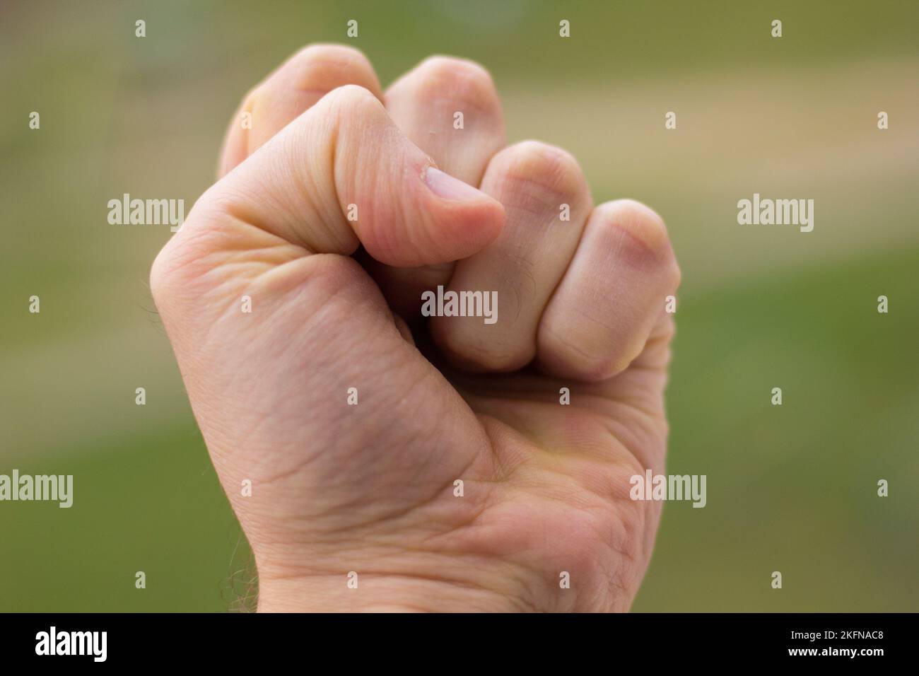 Mano stringendo un pugno su uno sfondo verde primo piano Foto Stock
