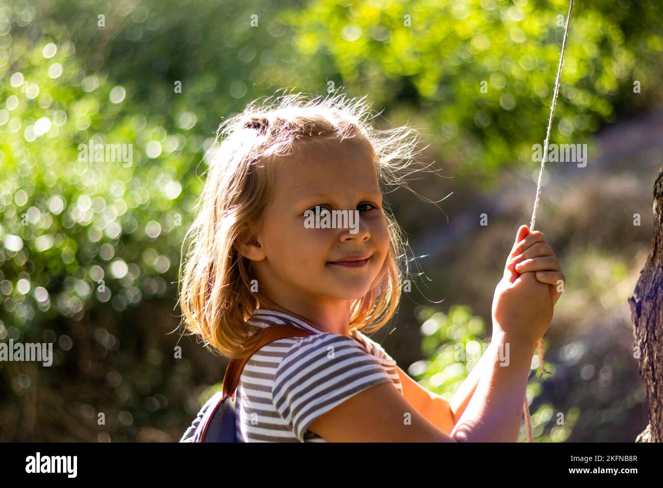 Bambina sorridente nel parco. Spazio di copia. Bambino felice che guarda la macchina fotografica. Ritratto di un ragazzo ridente fuori. Banner. Foto Stock
