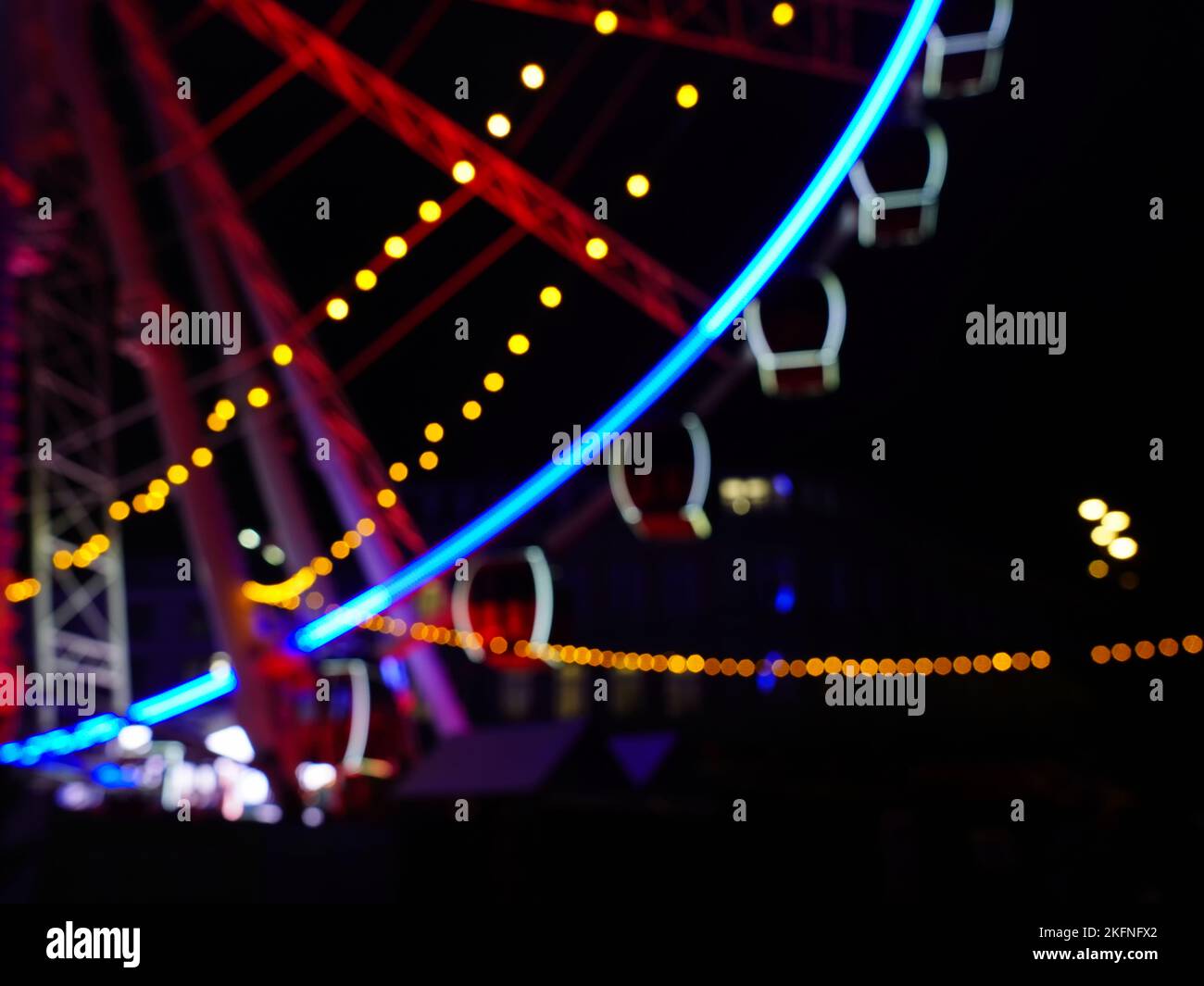 Immagine di sfondo sfocata di una ruota panoramica di notte con effetti bokeh. Foto Stock