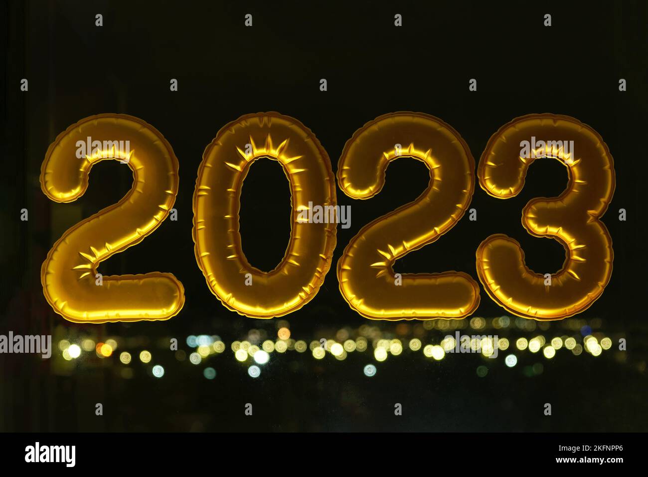 Palloncini gonfiabili d'oro numero 2023 sulla finestra sullo sfondo della città notturna, in luce al neon. Capodanno 2023, natale. Natale e Capodanno 2023. Foto Stock