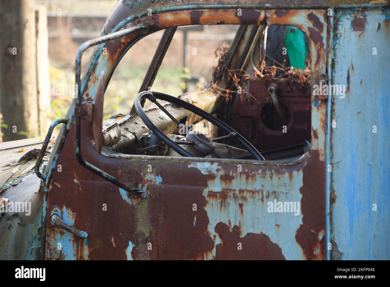 Un camion abbandonato arrugginisce, la vernice che era blu si toglie e scompare. L'interno della cabina è arrugginito e danneggiato. Foto Stock