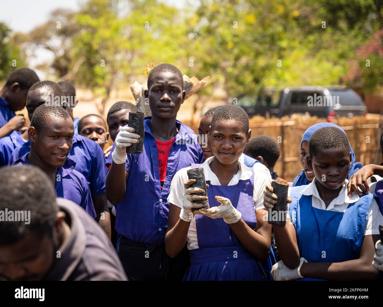 I chidlren della scuola secondaria a Nkhotakota, Malawi, presentano le piantine dell'albero durante una sessione di piantagione dell'albero nel loro randello ambientale. Foto Stock