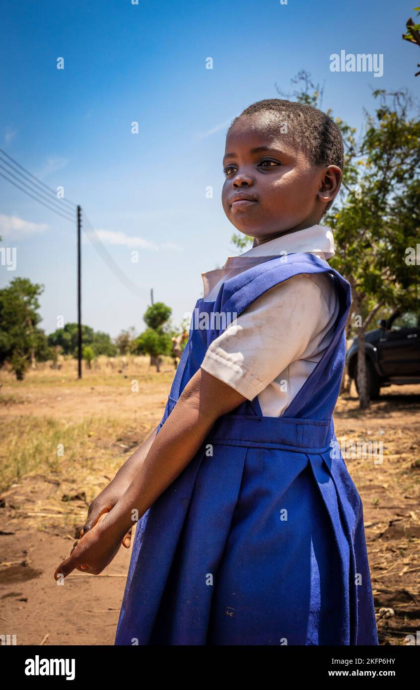 Una giovane ragazza in divisa scolastica in Malawi guarda avanti in modo assertivo Foto Stock