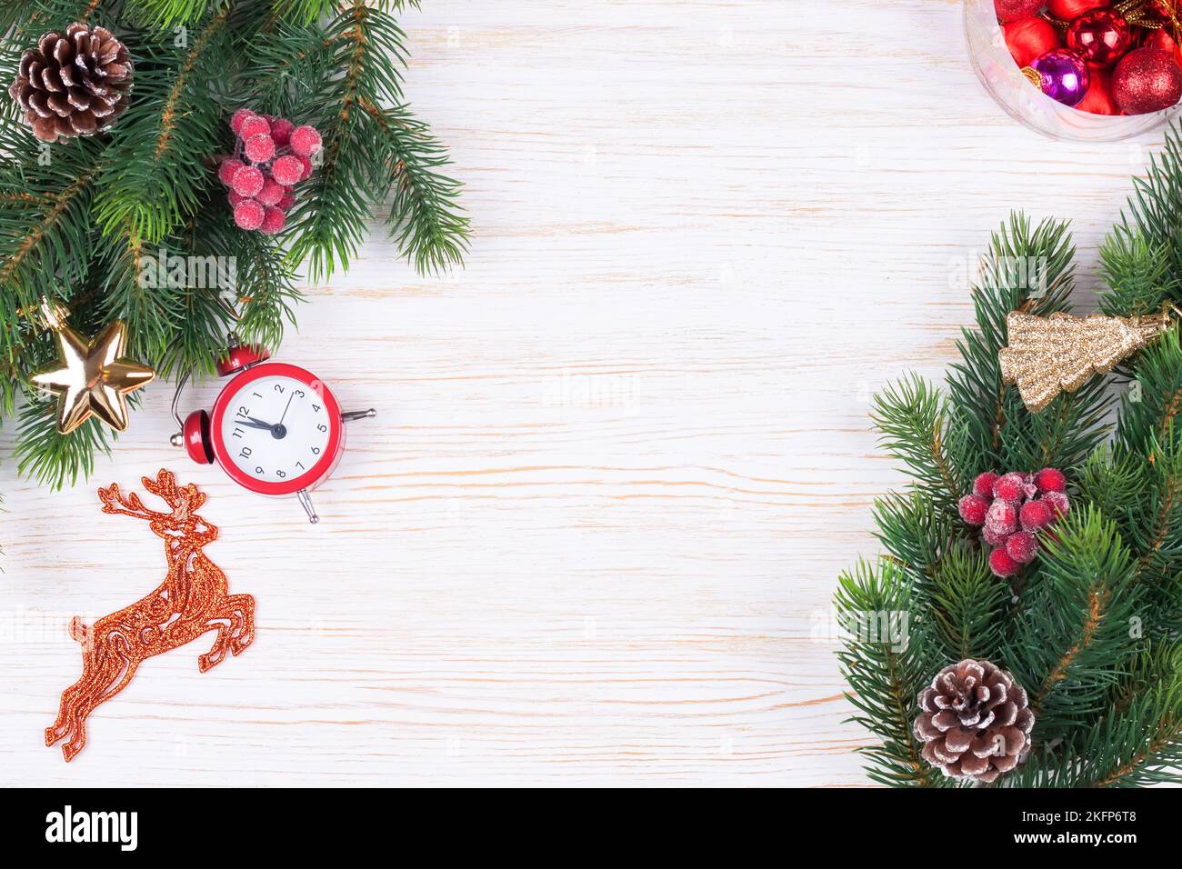 Composizione di Natale e Capodanno. Decorazioni natalizie, ramo di abete, ghirlanda, cappello rosso di babbo natale, orologio, regalo su sfondo bianco in legno. Piatto Foto Stock