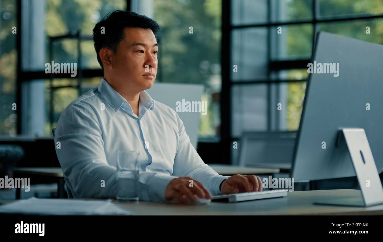 Professionista lavoratore maschio asiatico coreano uomo di successo imprenditore programmatore specialista sedersi in ufficio scrivania lavoro con il programma software per computer Foto Stock