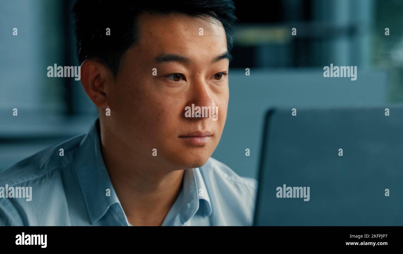 Primo piano ritratto cinese giapponese focalizzato uomo professionista asiatico coreano lavoratore web designer uomo d'affari lavoro con computer programma utilizzare computer portatile ufficio Foto Stock
