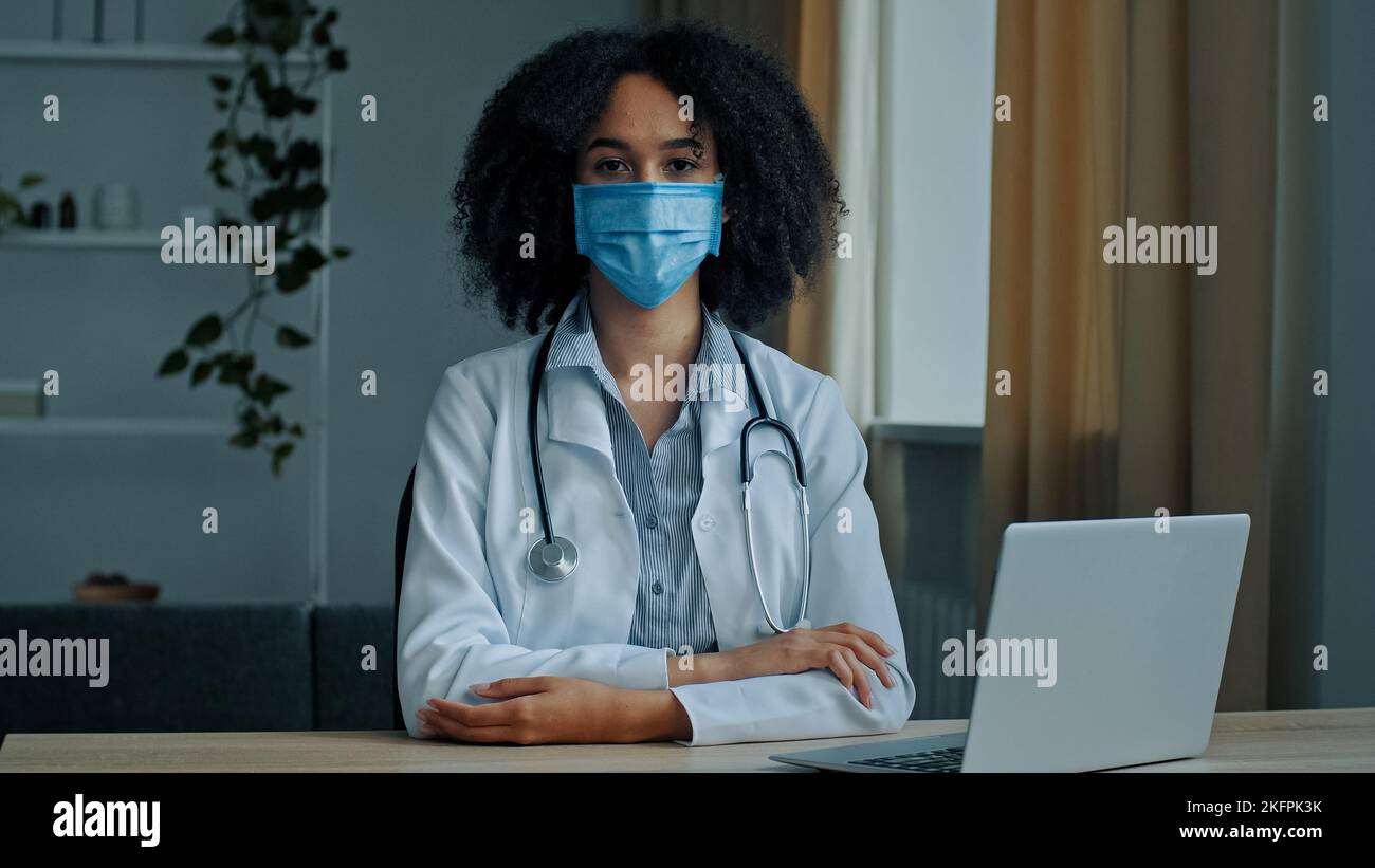Primo piano ritratto donna africana in maschera di protezione medica femmina medico infermiera terapista chirurgo psicologo professionista seduto in ospedale clinico Foto Stock