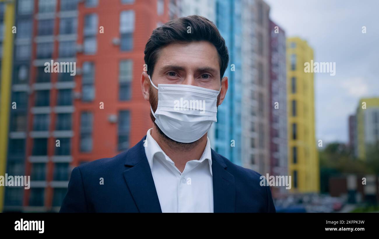 Primo piano ritratto di un uomo d'affari che indossa una maschera medica messo sul respiratore faccia seguire le misure di quarantena uomo che lavora sulla strada della città uso personale Foto Stock