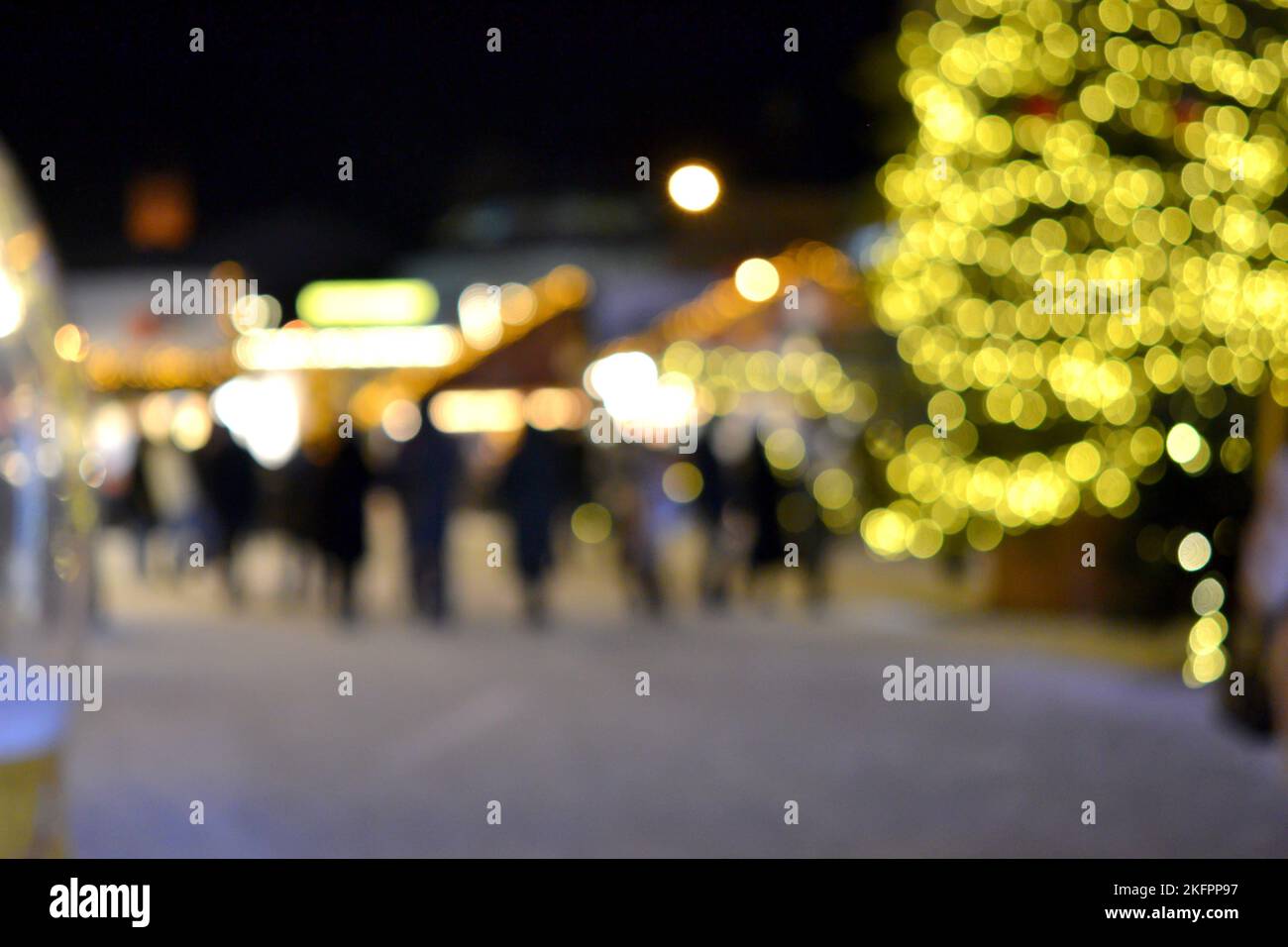 Sfondo sfocato. Albero di Natale, luci decorate, edificio, sagome sfocate di persone che camminano piazza della città durante la notte d'inverno. Bello Capodanno e Natale vacanza sfondo sfocato Foto Stock