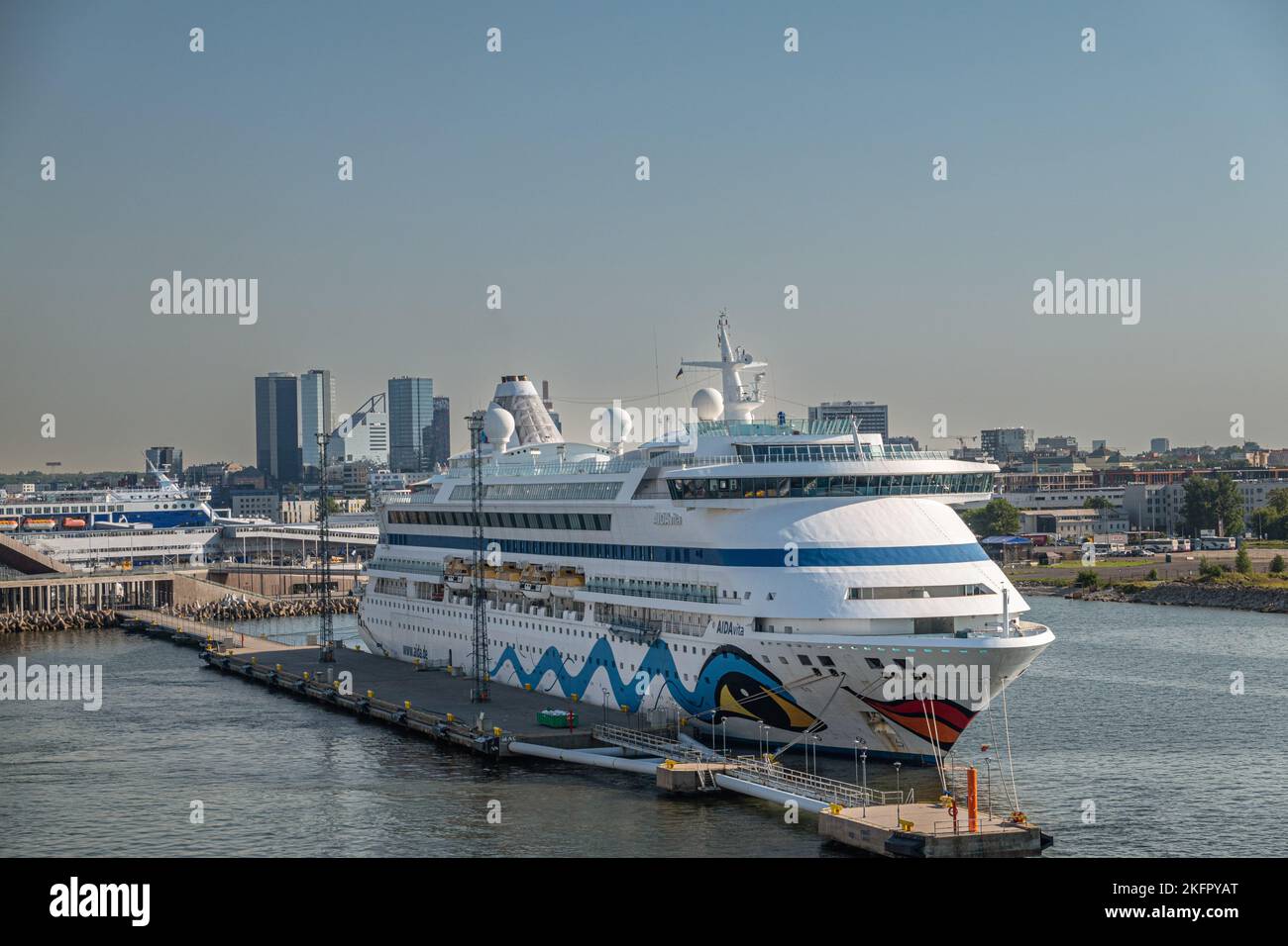 Estonia, Tallinn - 21 luglio 2022: Primo piano della nave da crociera bianca AIDAvita ormeggiata nel porto con un alto paesaggio urbano in fondo al cielo azzurro. Po. Più ampio Foto Stock
