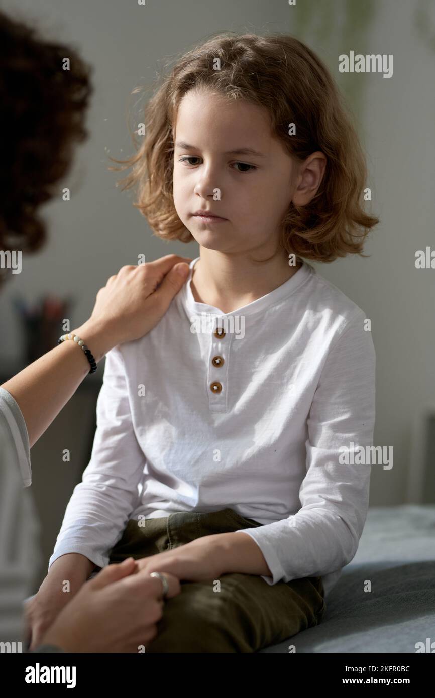 Ragazzino sconvolto che ascolta la mamma mentre parla del suo cattivo comportamento Foto Stock