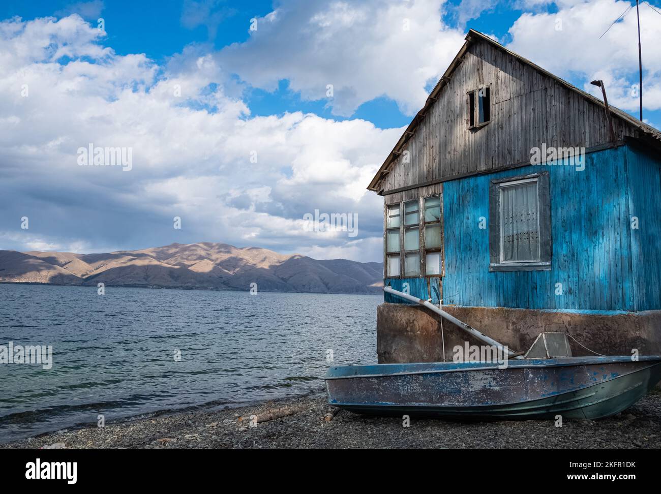 Vecchia casa di legno e una barca sulle rive del lago Sevan in Armenia. Foto Stock