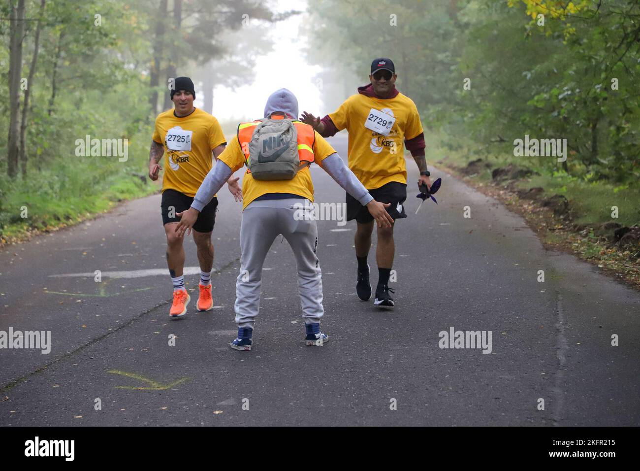 Una guardia stradale che incoraggia una coppia di corridori durante la prima corsa in ombra militare 10-miler in Polonia a Podwidz. I corridori che mostrano resistenza come i volontari e i Cheerleaders di Baltimora Ravens offrono incoraggiamento. Foto Stock Una guardia stradale che incoraggia una coppia di corridori durante la prima corsa in ombra militare 10-miler in Polonia a Podwidz. I corridori che mostrano resistenza come i volontari e i Cheerleaders di Baltimora Ravens offrono incoraggiamento. Foto Stock