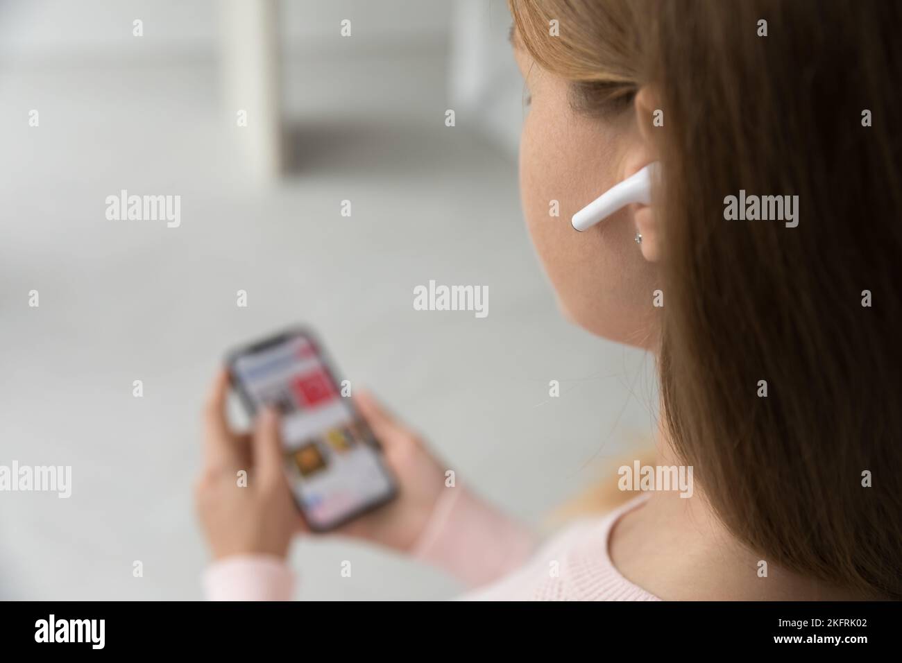 Donna sconosciuta indossa auricolari wireless per smartphone Foto Stock