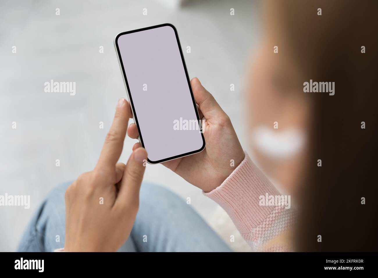 Donna che tiene in mano lo smartphone con schermo bianco mock-up, primo piano Foto Stock