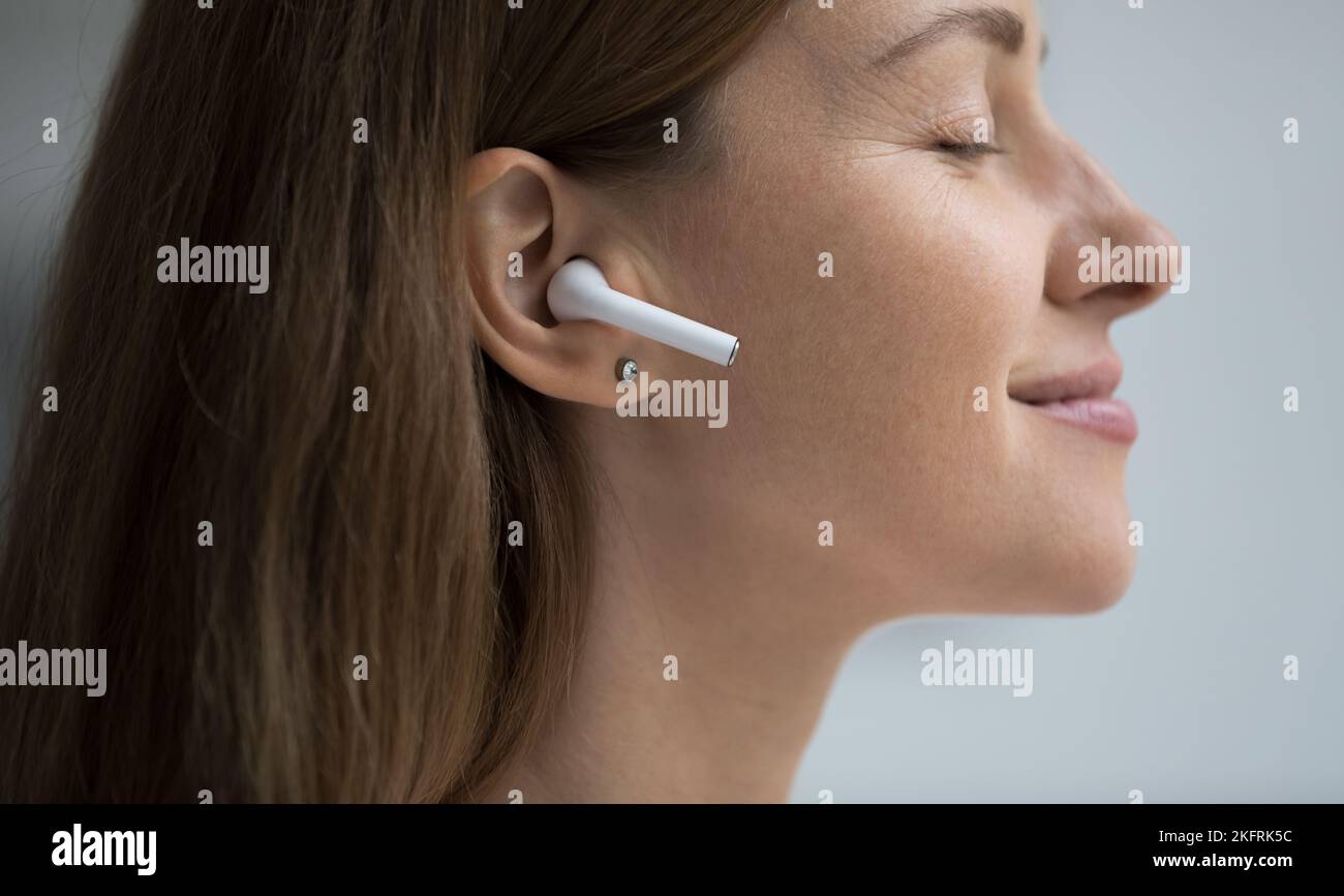 Donna godere di un suono di qualità attraverso auricolari wireless, primo piano Foto Stock