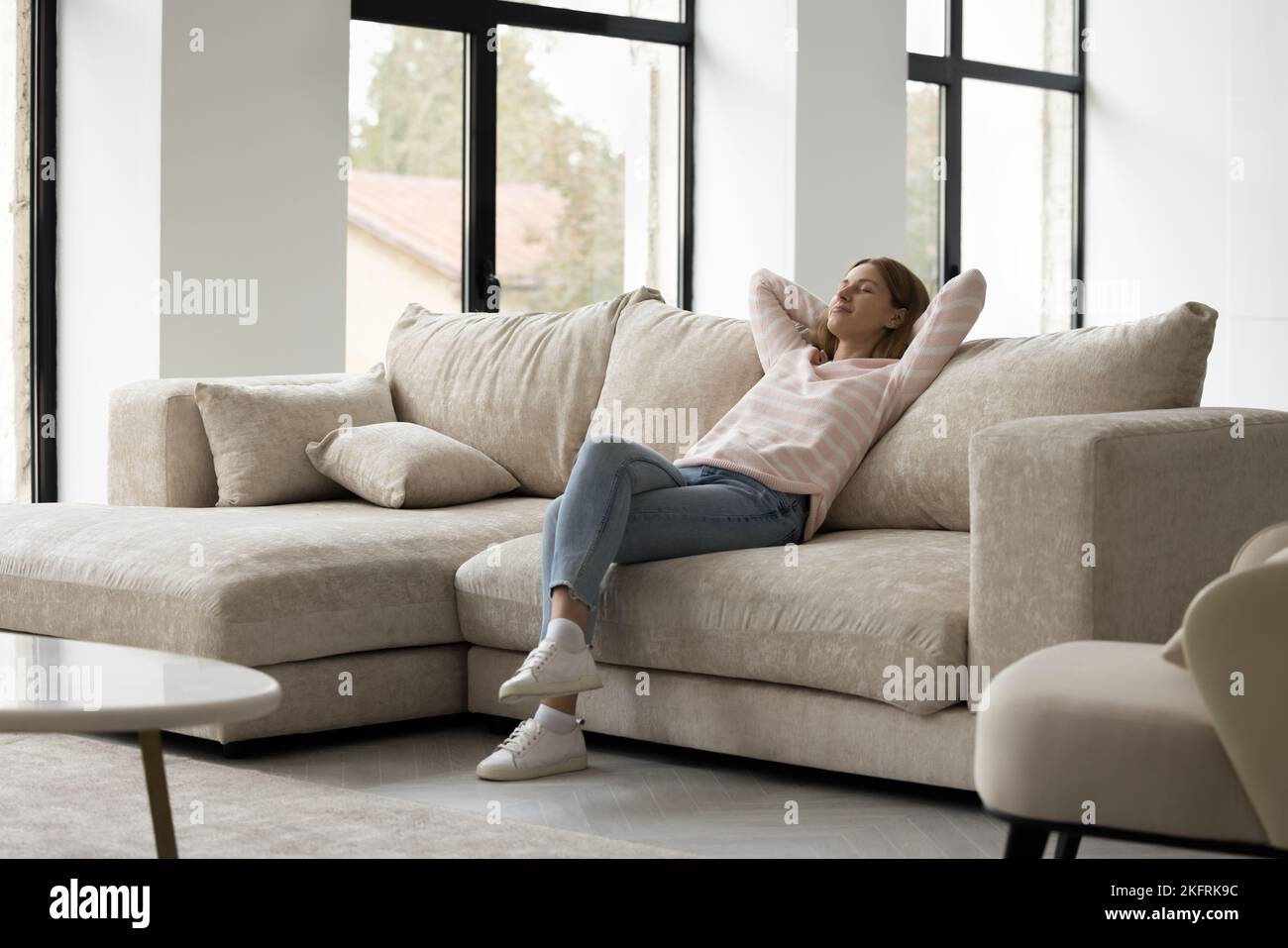 Donna in abiti casual trascorrere del tempo libero rilassandosi sul divano Foto Stock