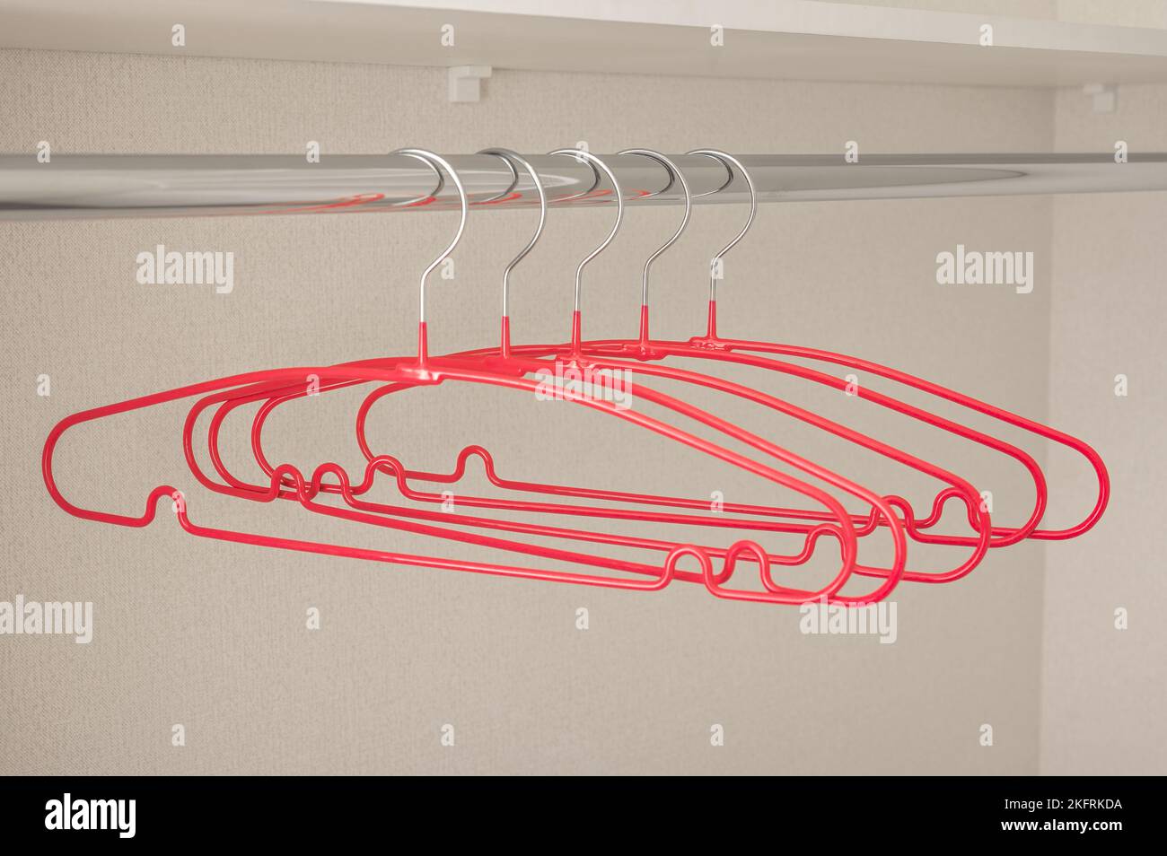 Molti appendiabiti rosa sul rack. Appendiabiti vuoto. Concetto del negozio, vendita, design, appendiabiti vuoto. Appendiabiti luminosi per cappotto e abiti su scaffale. Fila di cappotto rosa Foto Stock