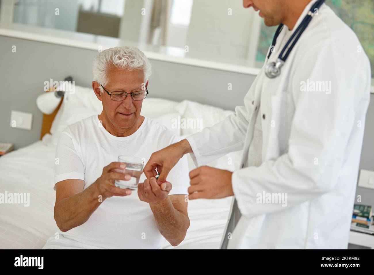 Tempo per i vostri meds. Un medico che dà al suo paziente anziano una dose di medicina ad una struttura vivente assistita. Foto Stock