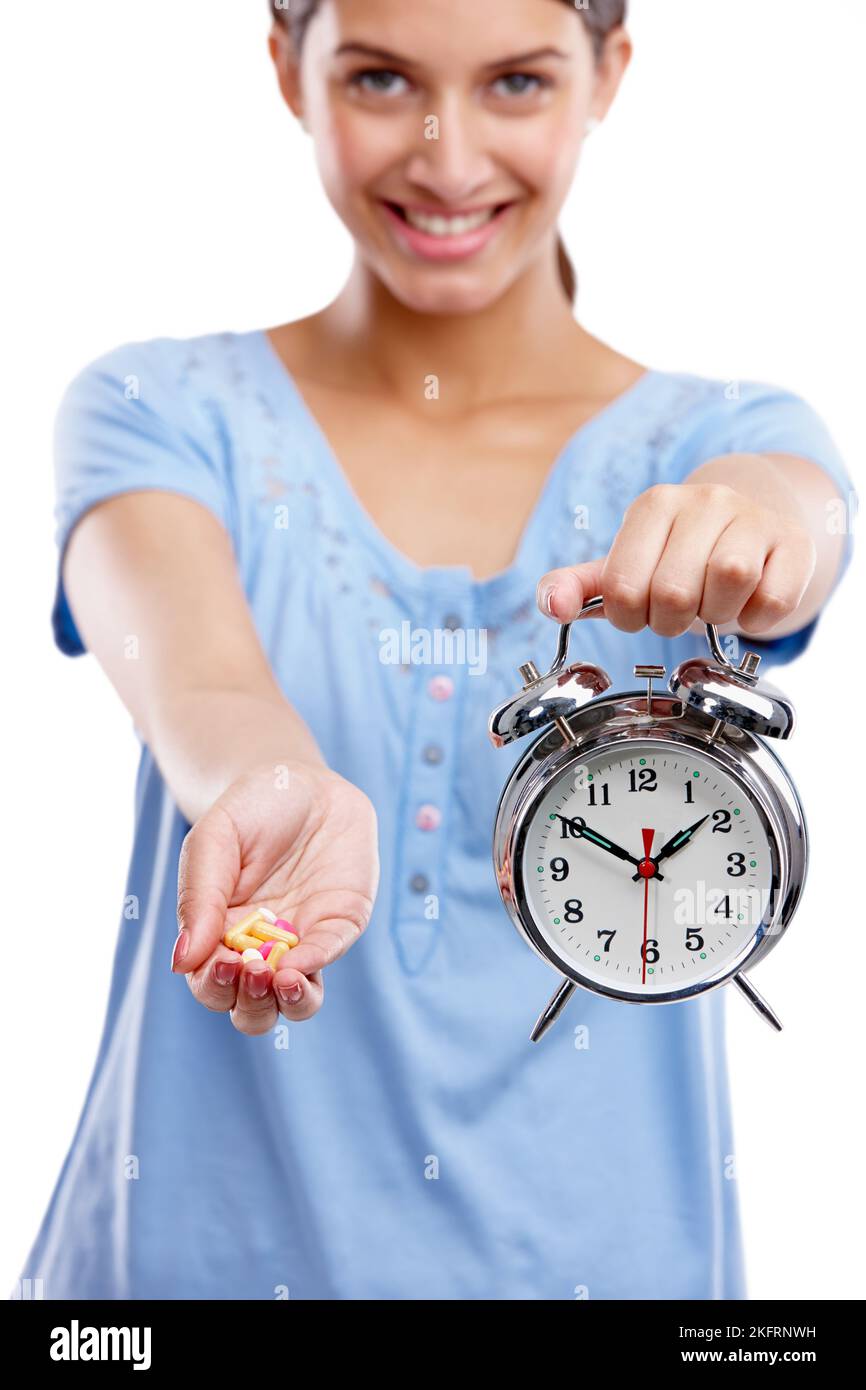 Tornare indietro l'orologio con vitamine quotidiane. Studio ritratto di una giovane donna con una manciata di tablet e un orologio. Foto Stock