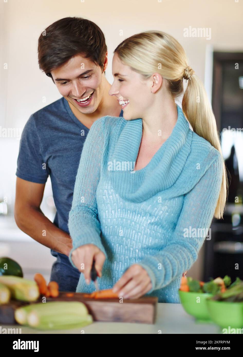 Sembra fantastico, miele. Una giovane coppia felice che condivide un momento affettuoso insieme mentre prepara un pasto. Foto Stock