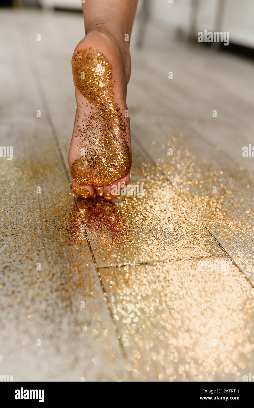 Gambe in glitter. La ragazza cammina sull'oro. La ragazza alla festa di Capodanno va per i confetti. Foto Stock