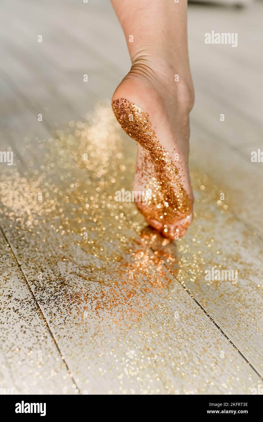 Gambe in glitter. La ragazza cammina sull'oro. La ragazza alla festa di Capodanno va per i confetti. Foto Stock