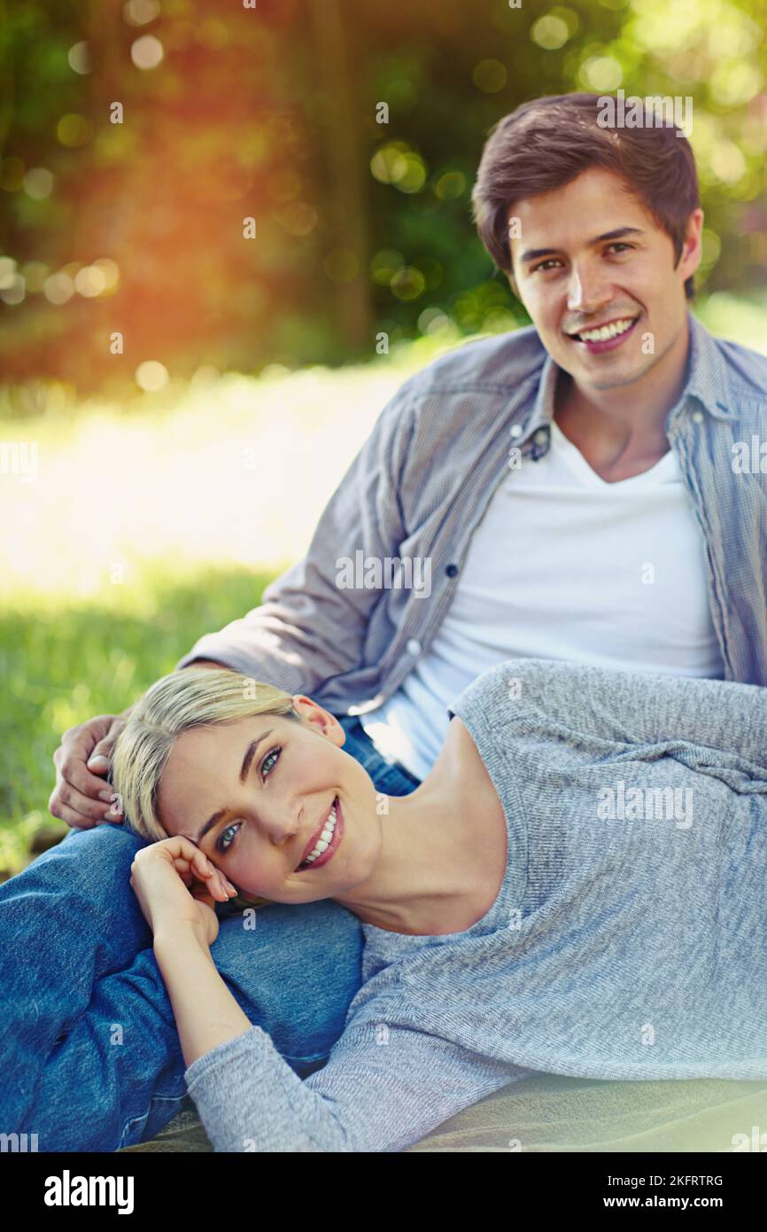 Il loro amore è tutto naturale: Una giovane coppia felice sdraiata sull'erba e che condivide insieme un momento affettuoso. Foto Stock