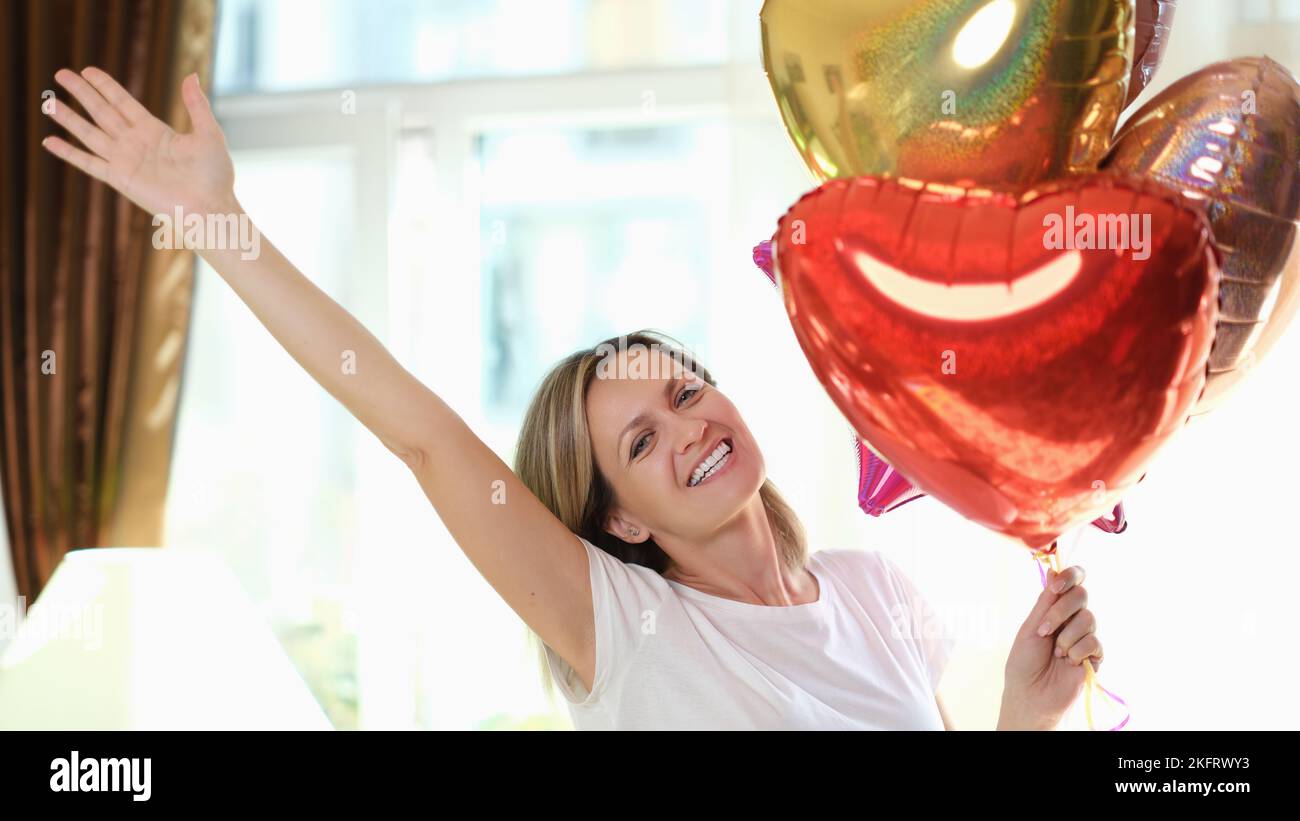 Donna sorridente felice con palloncini d'aria per festeggiare il compleanno a casa. Foto Stock