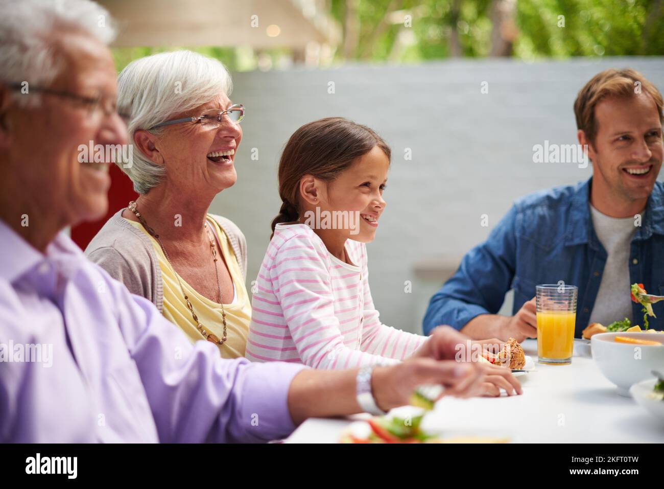 Godetevi una giornata in famiglia. Una famiglia felice multi-generazionale che ha un pasto insieme all'esterno. Foto Stock