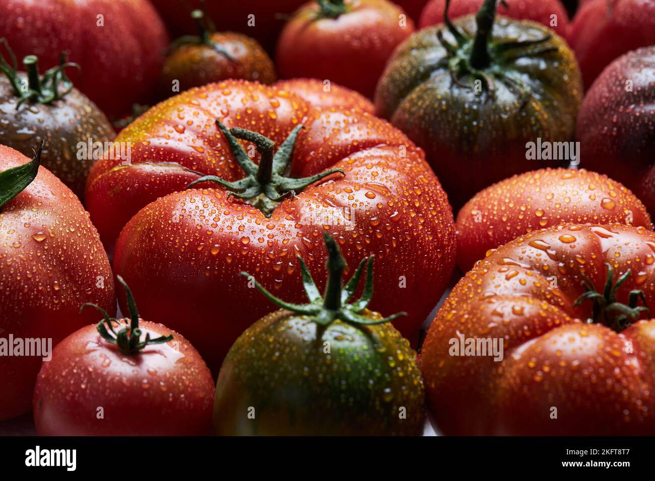 Dall'alto di appetitosi pomodori freschi maturi con gocce d'acqua con foglie verdi Foto Stock