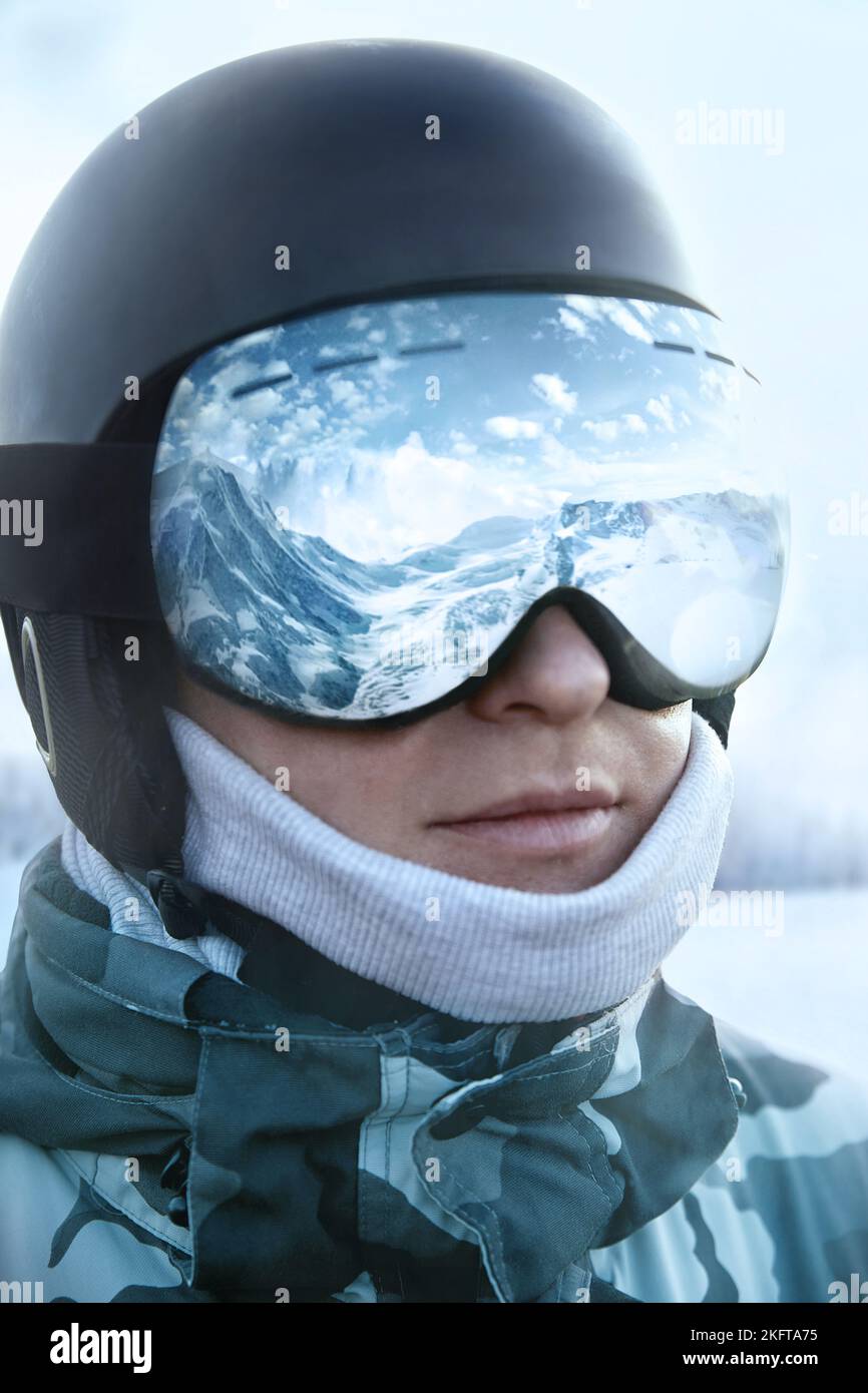 Occhiali da sci con il riflesso delle montagne innevate. Uomo sullo sfondo cielo blu. Sport invernali. Foto Stock