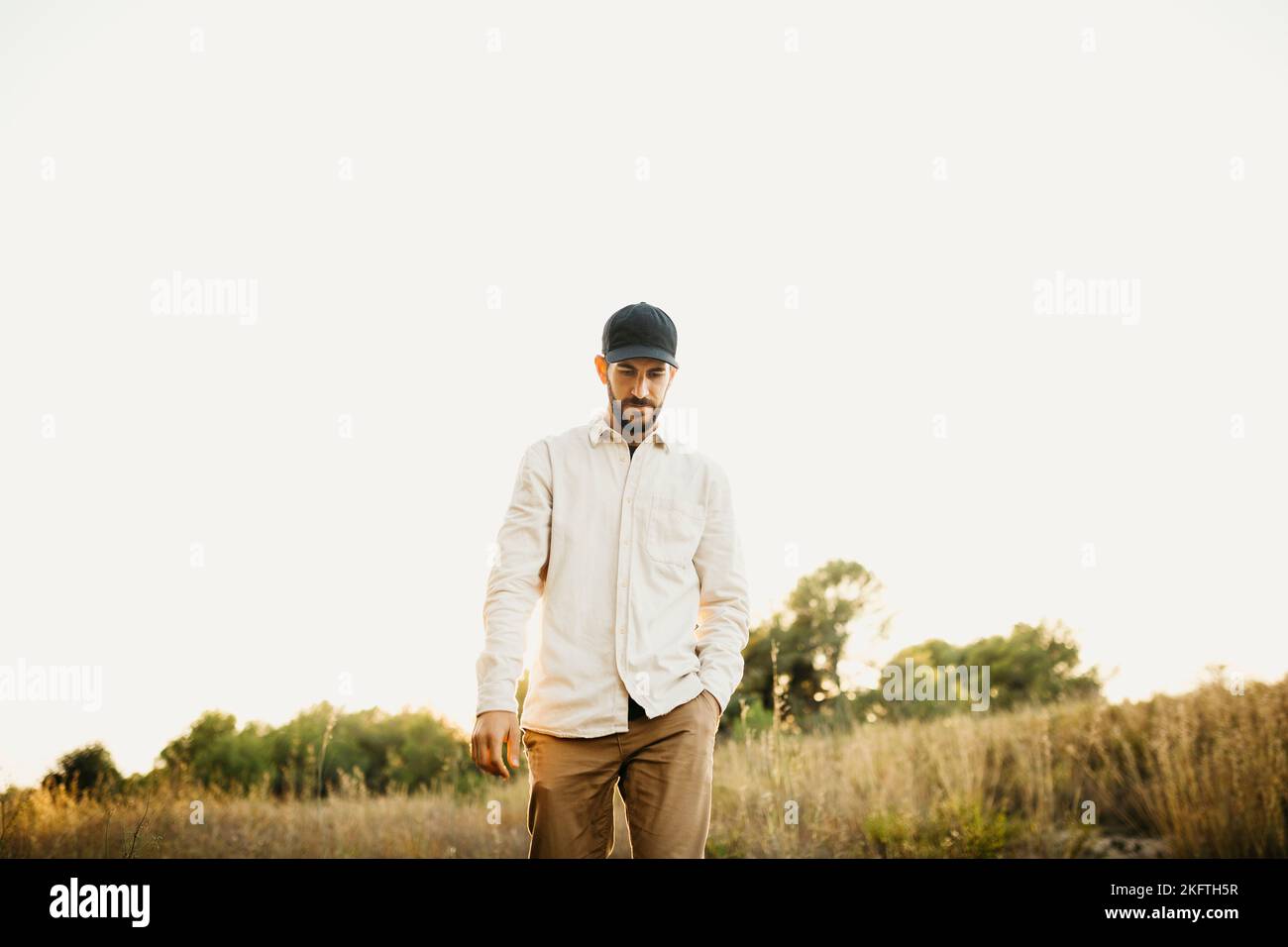 Ritratto di un giovane barbuto che indossa un cappellino nero, con il cane, in campagna Foto Stock