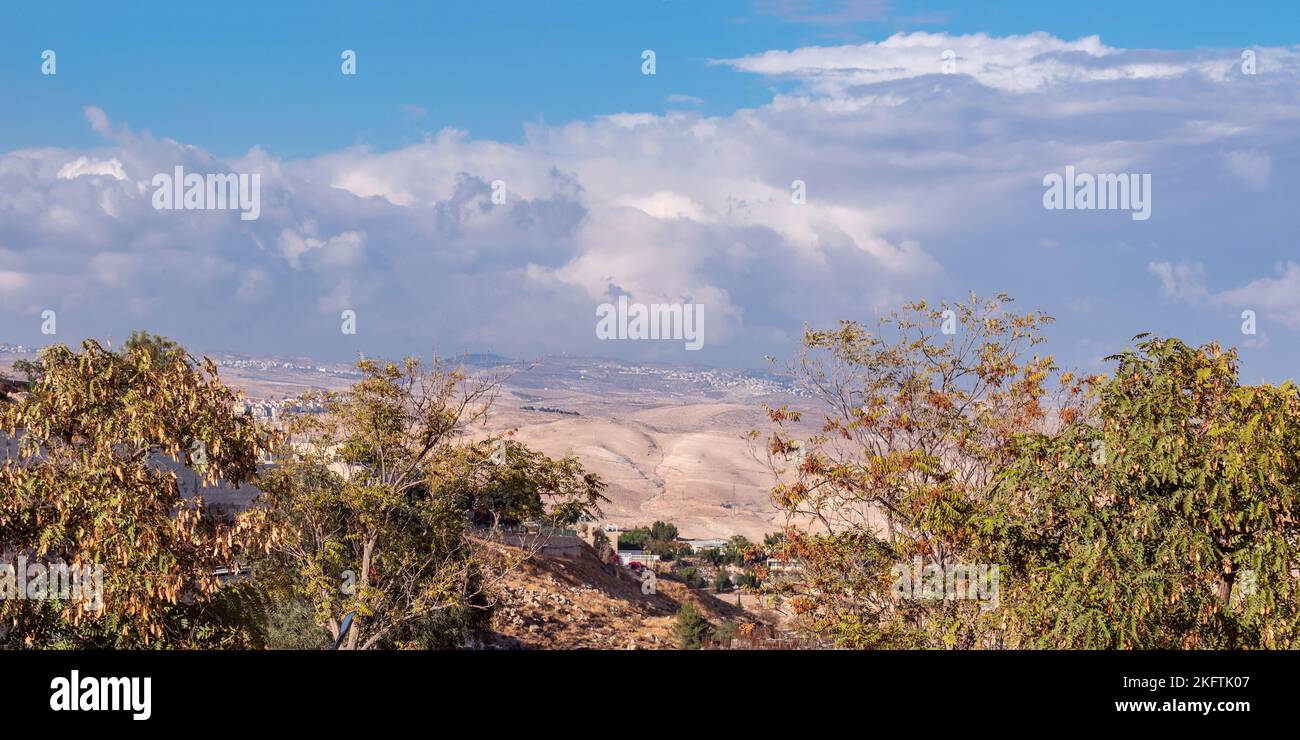 Panorama del cielo blu e delle nuvole sopra gli alberi con colori autunnali a Maale Adumim in Israele con villaggi palestinesi sullo sfondo Foto Stock