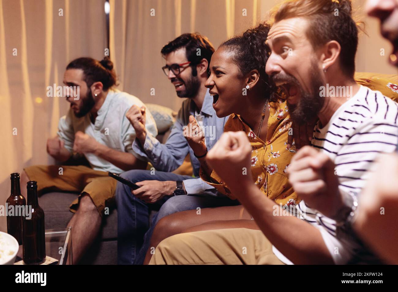 Amici sostenitori del calcio che guardano la partita di calcio in TV e celebrano la vittoria Foto Stock