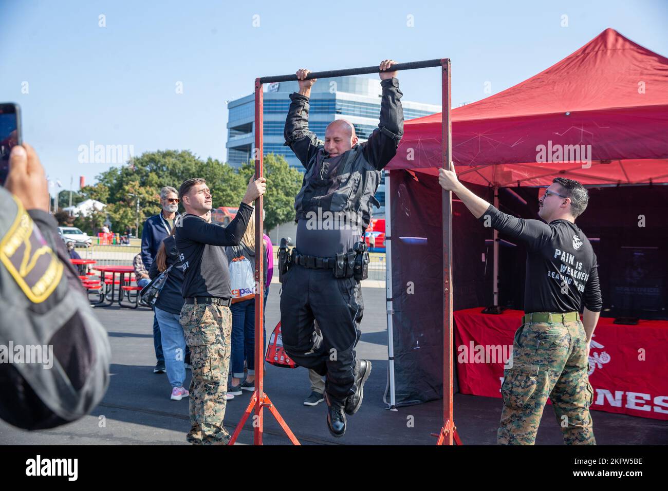 Una pattuglia della North Carolina state Highway Patrol tenta la sfida del pull up bar prima della gara NASCAR Cup Series al Charlotte Motor Speedway, Concord, North Carolina, 9 ottobre 2022. Il Bank of America ovale 400 è una gara della serie NASCAR Cup che si svolge ogni anno presso l'autodromo di Charlotte e che ospita eventi musicali e feste per famiglie e partecipanti di tutte le età. I Marines del 6th Marine Corps District hanno mostrato il supporto per l'evento con la sfida pull-up, il veicolo di marketing migliorato e la posizione di battaglia. Foto Stock