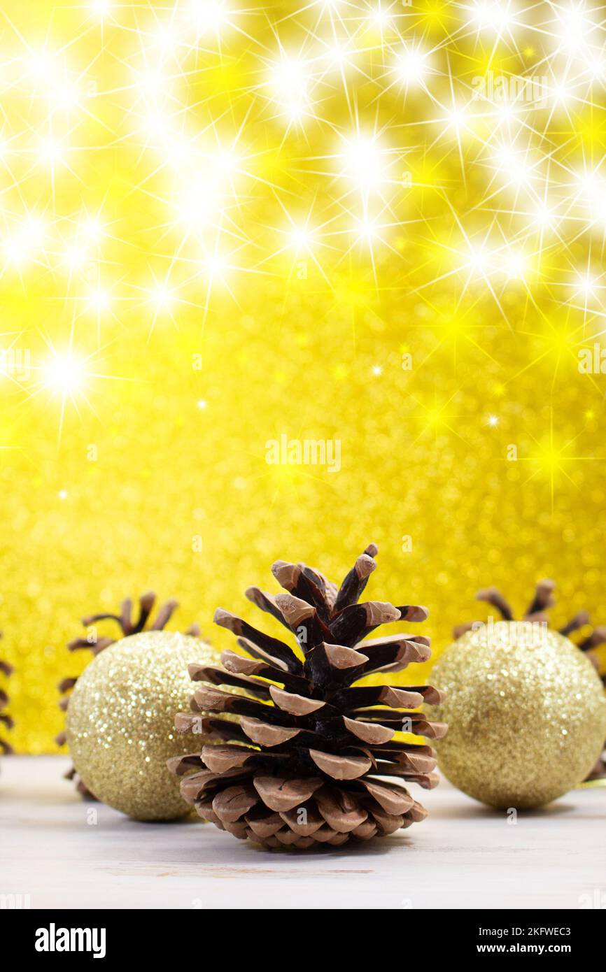 Coni di pino con palline lucenti sul fondo giallo dorso lucido con stelle. Natale, Capodanno. Verticale. Spazio di copia Foto Stock