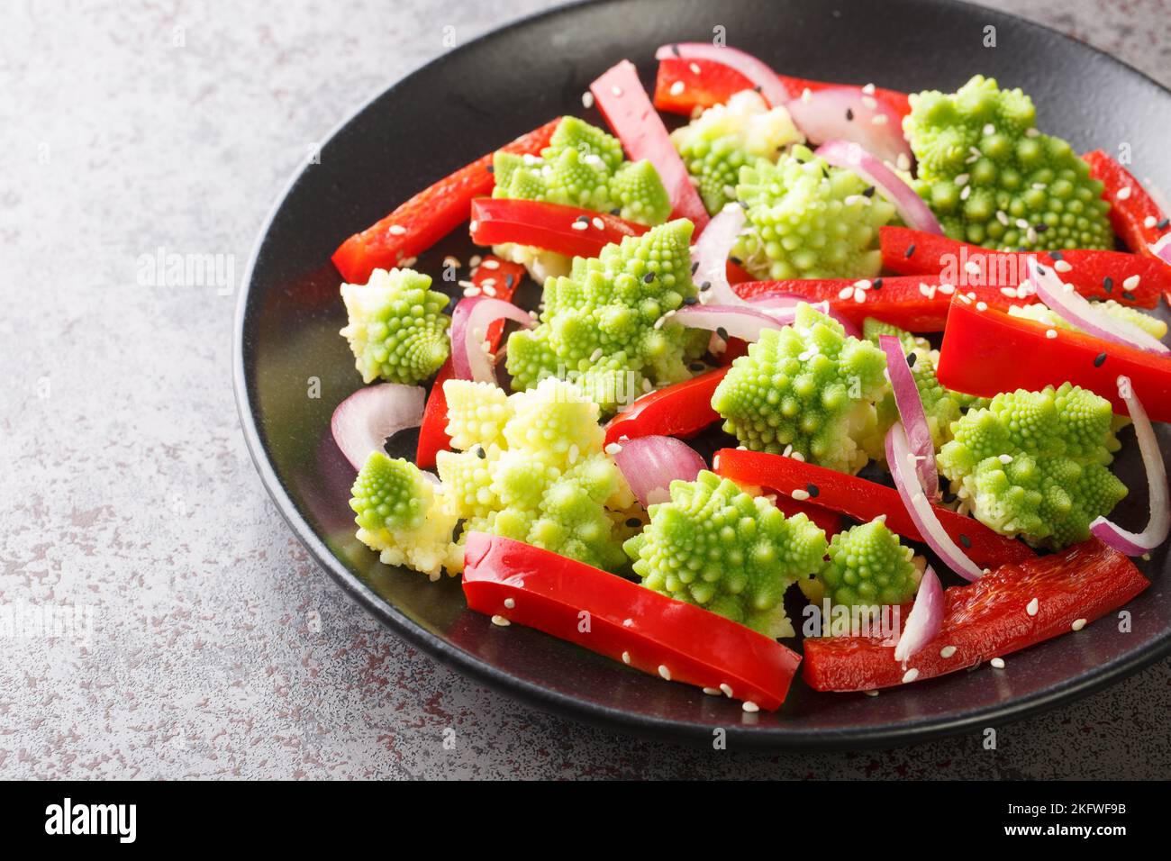 Insalata vegana di verdure fresche e cavolo romanesco primo piano in un piatto sul tavolo. Orizzontale Foto Stock