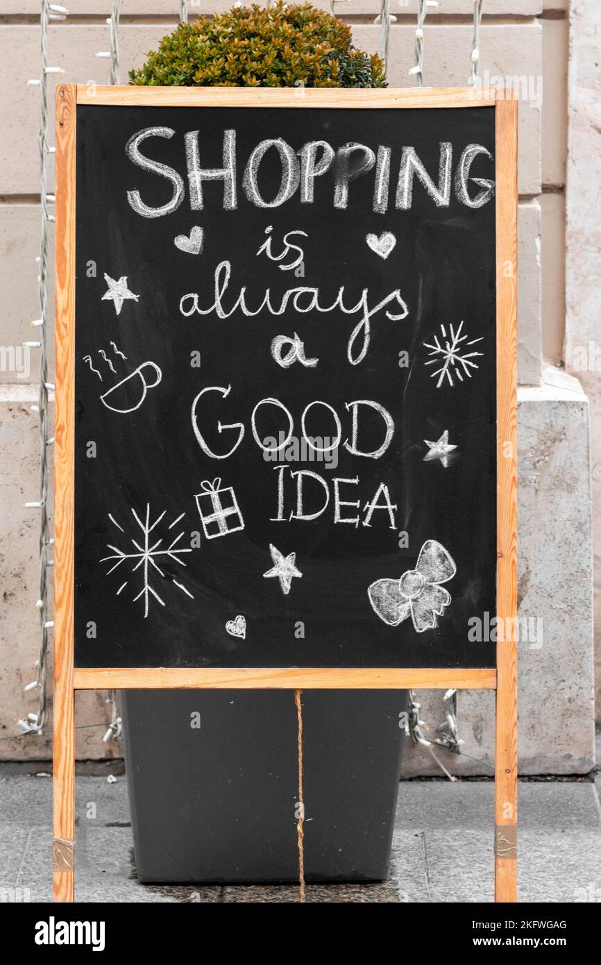 Lo shopping è sempre un cartello commerciale di buona idea scritto su una lavagna con disegni festosi di fronte a un negozio nel centro della città Foto Stock