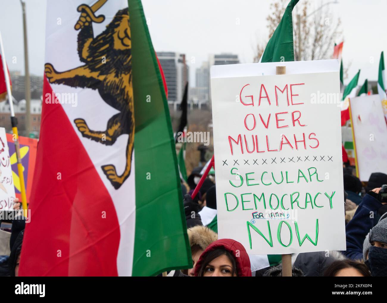 Un segno cade per una democrazia secolare per l'Iran, tenuta vicino ad un leone pre-regime e bandiera del sole, durante un evento a North York, Ontario. Foto Stock