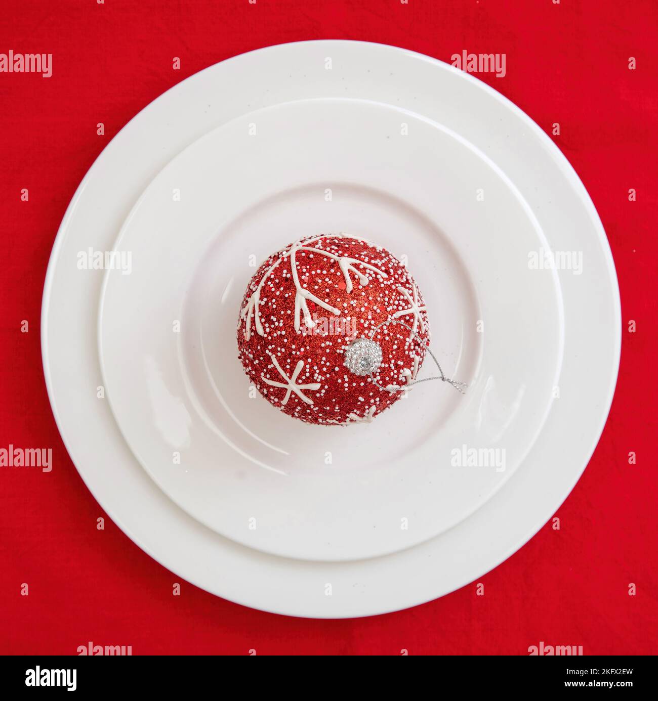 Tabella di Natale impostazione. Natale bauble su piatti su sfondo rosso, vista dall'alto. Cena festiva Foto Stock
