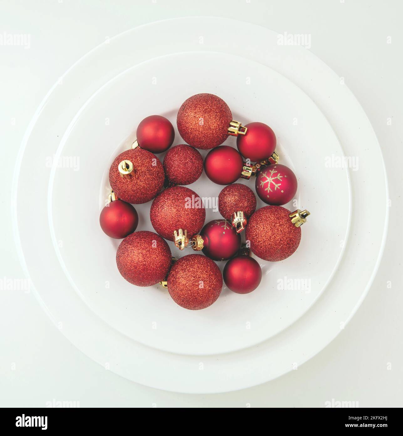 Cena di festa, tavolo di Natale con vista dall'alto. Rosso Natale baubles su piatti isolati su sfondo bianco, vista dall'alto. Foto Stock