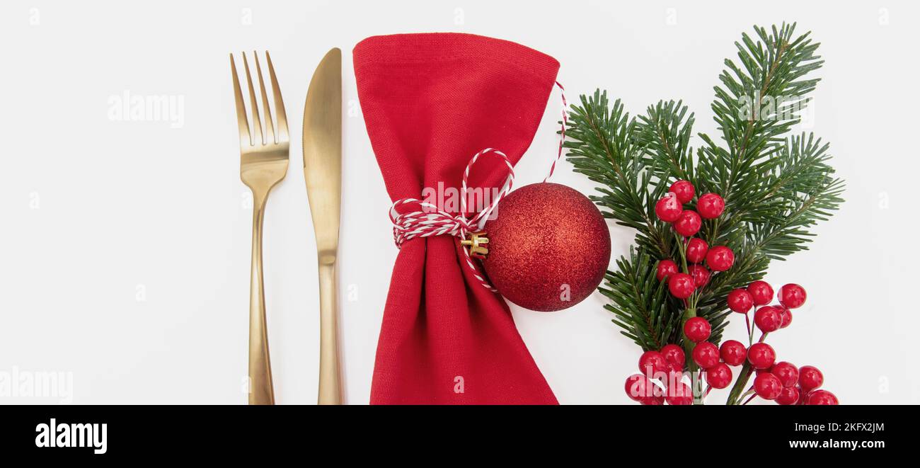 Tavolo di Natale, cena di festa. Posate dorate e tovagliolo rosso su sfondo bianco, vista dall'alto Foto Stock