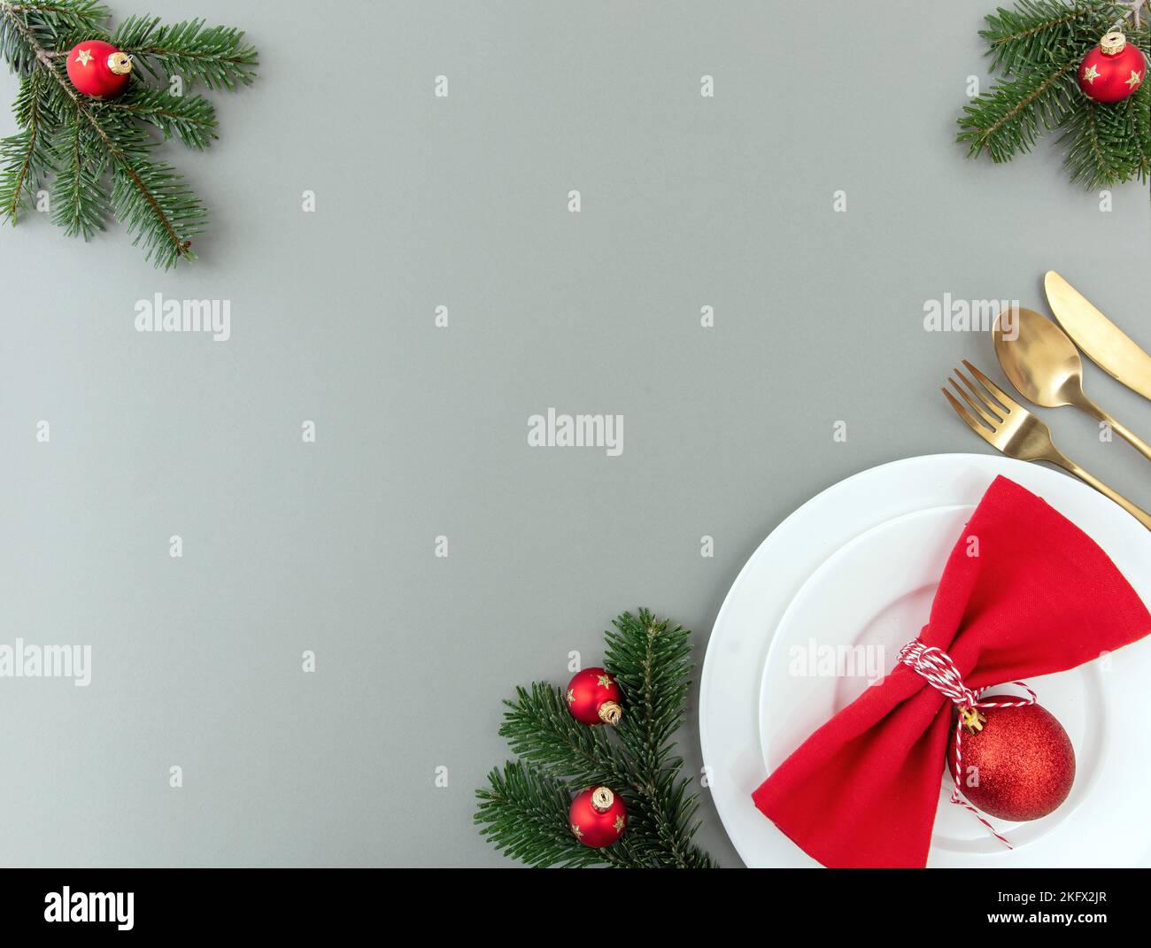 Tavolo di Natale impostazione, festa cena piatto laici. Posate dorate, tovagliolo rosso e decorazione natalizia su sfondo grigio, vista dall'alto, spazio copia Foto Stock