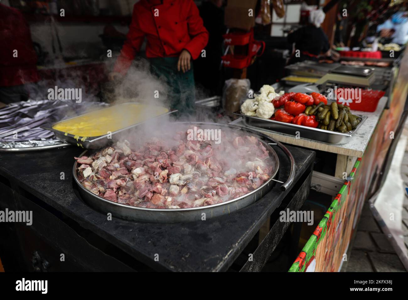 Profondità di campo bassa (fuoco selettivo) dettagli con una grande padella con carne, con polenta e sottaceti vicino, a Bucarest, Romania. Foto Stock